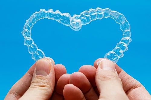 Invisalign Aligners Being Held Together In The Shape Of a Heart